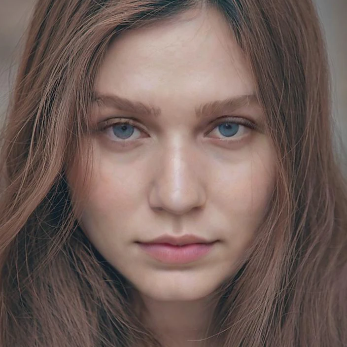 Close-up of a woman with long brown hair looking straight at the camera, before the v2 update
